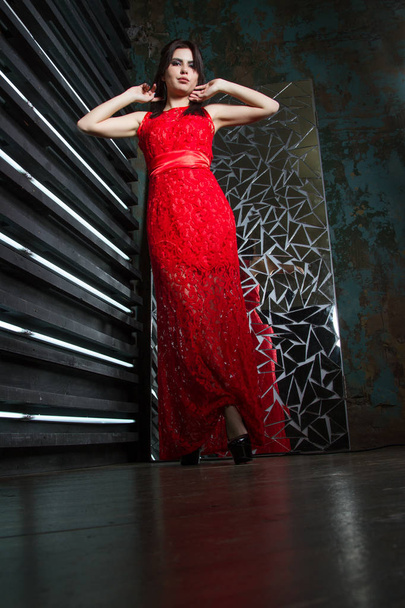 κορίτσι σε ένα σκοτεινό δωμάτιο, σε ένα μακρύ κόκκινο φόρεμα - Φωτογραφία, εικόνα