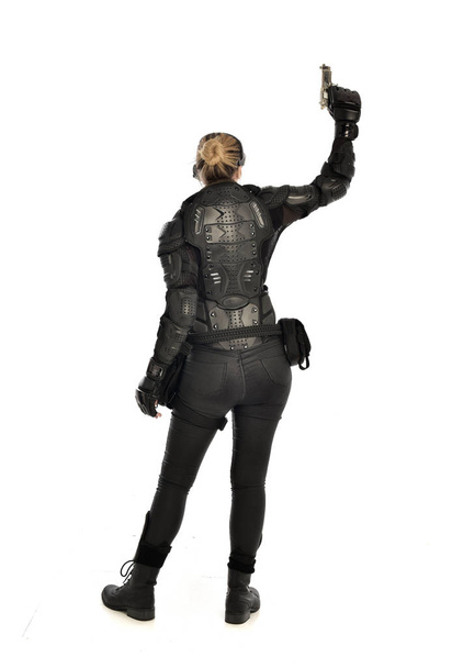 Tam boy siyah taktik zırh giyen, beyaz stüdyo arka plan üzerinde izole bir silah tutan kadın asker portresi. - Fotoğraf, Görsel