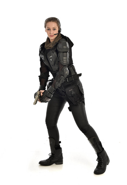 portrait complet d'une femme soldat portant une armure tactique noire, tenant un pistolet, isolée sur fond de studio blanc
. - Photo, image