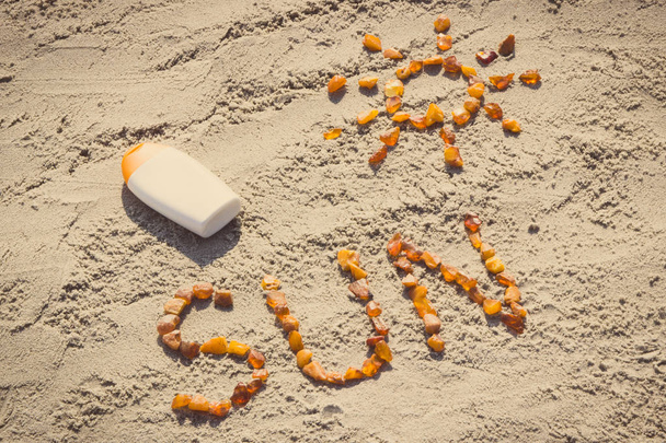 Vintage photo, Word and shape of sun, sun lotion on sand at beach, summer time concept - Foto, Imagem