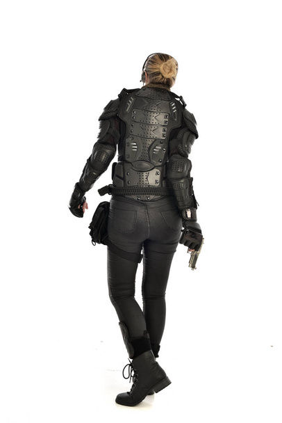 retrato de comprimento total de soldado vestindo armadura tática preta, segurando uma arma, isolado no fundo do estúdio branco
. - Foto, Imagem