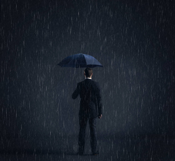 Businessman with umbrella standing under the rain. Dark, dramatic background. Business, failure, crisis, concept.  - Photo, Image