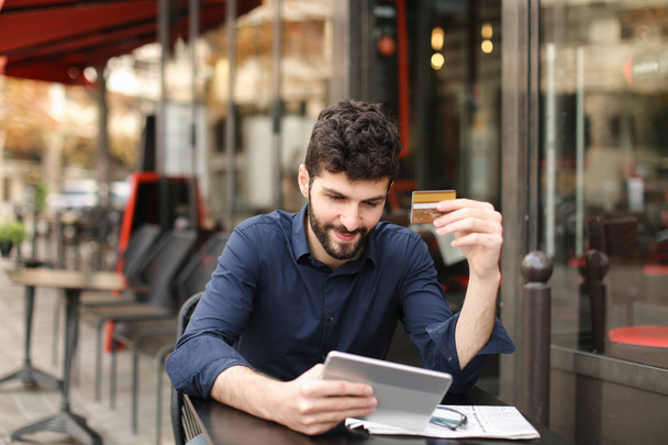 Hombre descontento jugando juego en línea por tableta en la cafetería de la calle
. - Foto, imagen