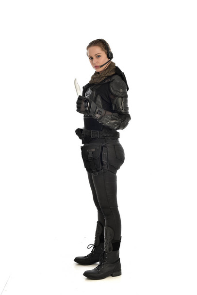 full length portrait of female  soldier wearing black  tactical armour, holding a knife, isolated on white studio background. - Photo, Image