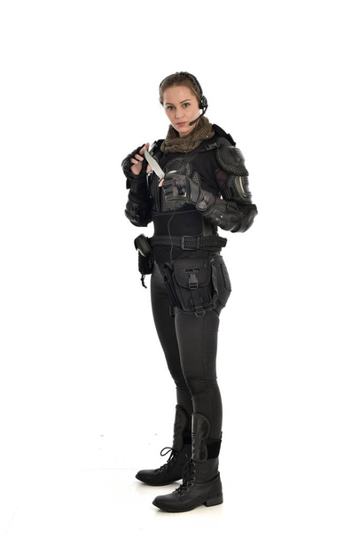 ritratto a figura intera di soldato donna che indossa un'armatura tattica nera, con in mano un coltello, isolato su sfondo bianco
. - Foto, immagini
