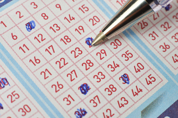 Closeup of hand marking number on lottery ticket with pen. - Photo, Image