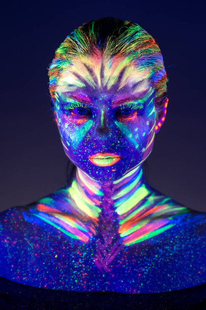 Portrait of beautiful girl with ultraviolet paint on her face. G - Photo, image