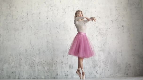 bailarina na ponta está girando na ponta dos pés. bailarino de balé em um pacote clássico em um contexto de uma parede leve
 - Filmagem, Vídeo