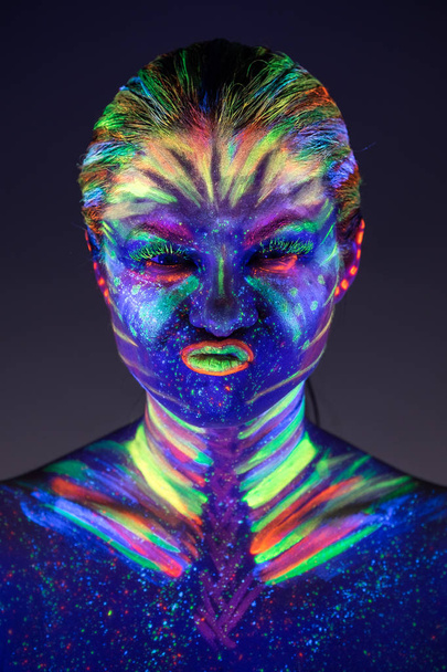 Portrait of beautiful girl with ultraviolet paint on her face. G - Foto, immagini