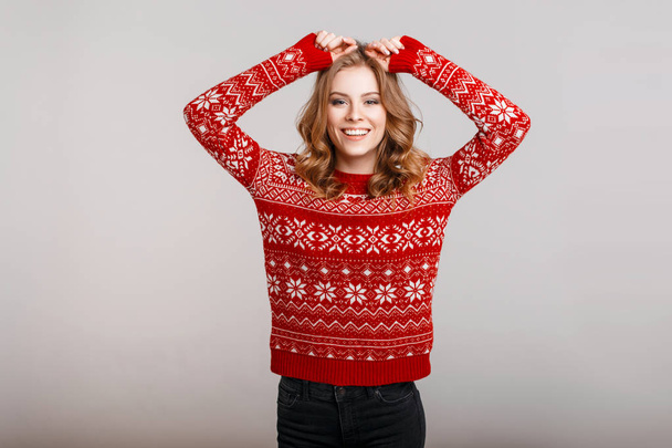 Смешная счастливая женщина в зимнем красивом винтажном свитере с эмблемой на заднем плане
 - Фото, изображение