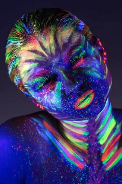Portrait of beautiful girl with ultraviolet paint on her face. G - Фото, изображение