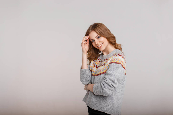 Молодая счастливая женщина в винтажном свитере на сером фоне
 - Фото, изображение