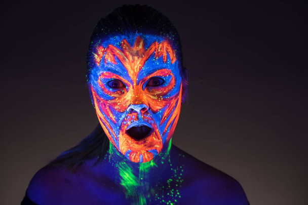 Portrait of beautiful girl with ultraviolet paint on her face. G - Foto, immagini