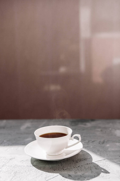 weiße Tasse schwarzen Tee auf einer Untertasse auf grauem Betongrund - Foto, Bild