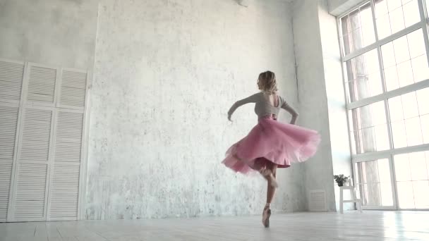 Baletní tanečník se točí v klasické tutu a pointe boty. Mladá baletka tance na špičkách na pozadí velké světlo okna - Záběry, video