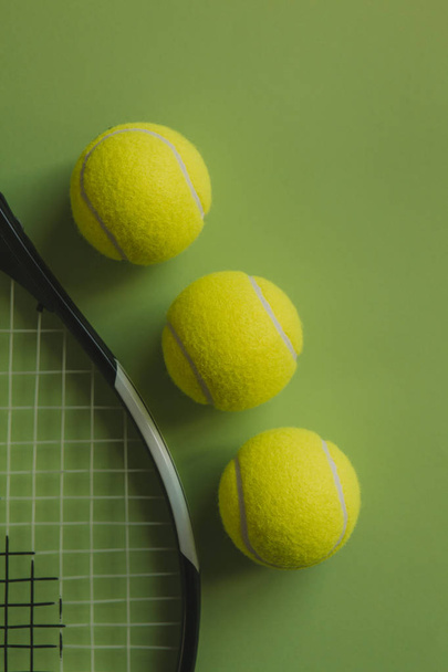 Three tennis balls and a tennis racket on green background. - Foto, Bild