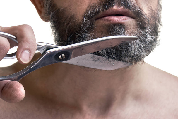 Keski-ikäinen mies leikkaa partansa suurilla saksilla
 - Valokuva, kuva