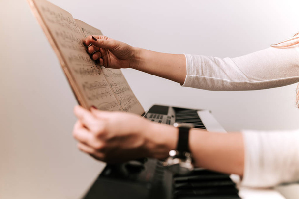 female hand holding classical sheet music for piano playing - 写真・画像