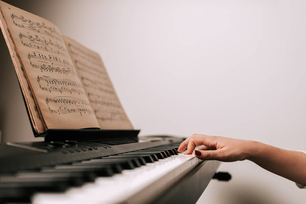 Female hand playing piano from classical sheet music - Φωτογραφία, εικόνα