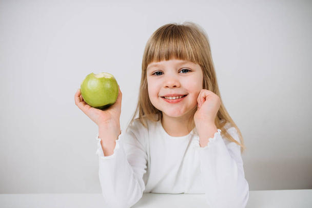 Portrait of little girl holding green apple - 写真・画像