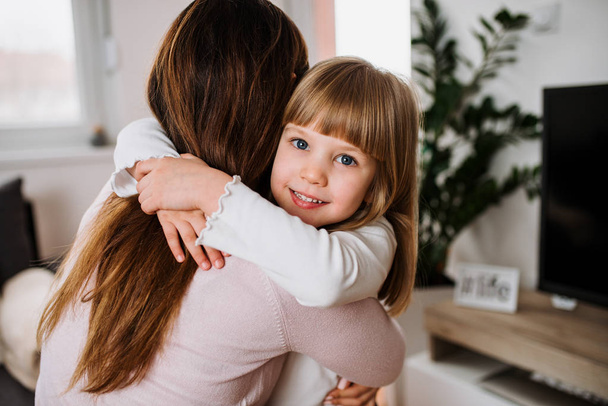Smiling girl hugging her mother at home - Fotoğraf, Görsel