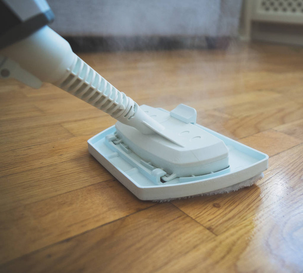 Καθαρίζοντας το πάτωμα με ένα ξηρό καθαριστής ατμού. - Φωτογραφία, εικόνα