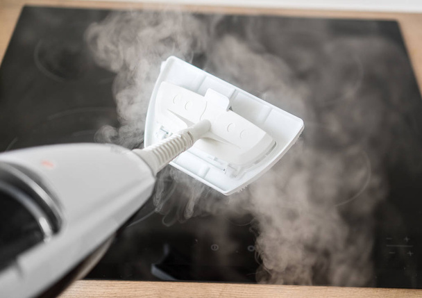 Cleaning kitchen hob with a steam cleaner. - Foto, afbeelding