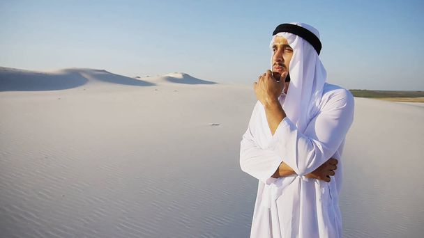 Stately Arabian UAE Sheikh man looks hard into distance and pond - Photo, Image
