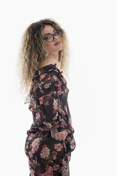 Woman with curly hair and floral dress posing on white background - Foto, afbeelding