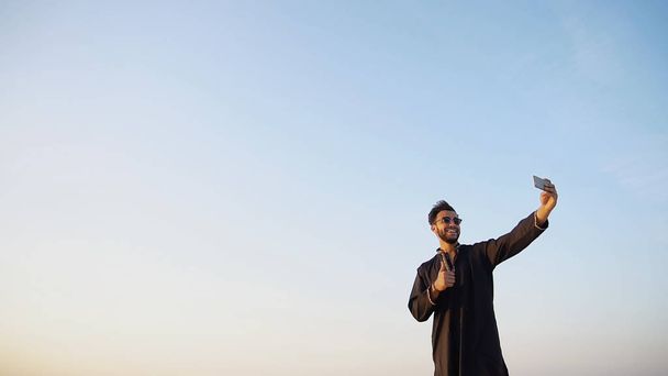 Homem moderno árabe viajante detém smartphone e tira fotos de oi
 - Foto, Imagem