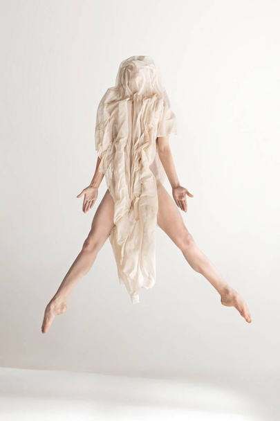 Young beautiful dancer in beige swimsuit dancing on gray background - Foto, afbeelding