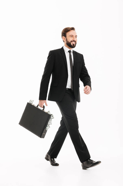 Happy young businessman with suitcase walking isolated - Fotó, kép