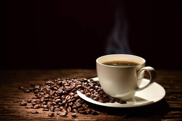 Tasse de café avec de la fumée et des grains de café sur fond noir
 - Photo, image