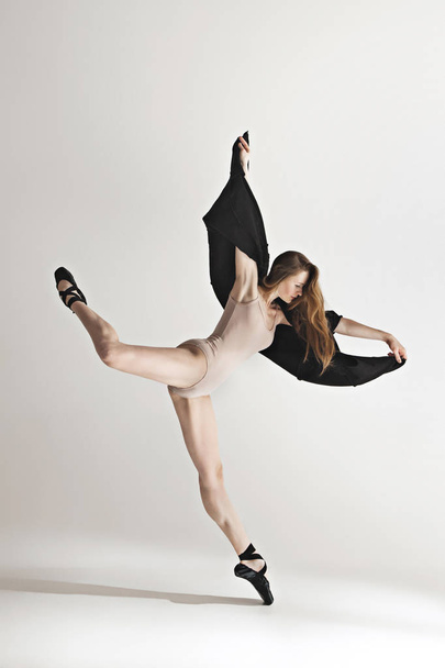 Young beautiful dancer in beige swimsuit dancing on gray background - Foto, immagini