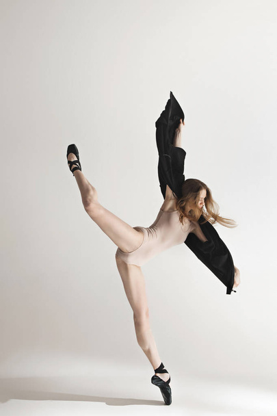 灰色の背景の上で踊ってベージュの水着で若い美しいダンサー - 写真・画像