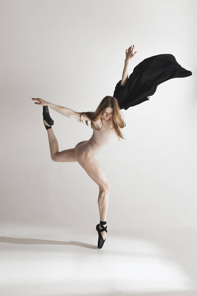 Молодая красивая танцовщица в бежевых купальниках танцует на сером фоне
 - Фото, изображение