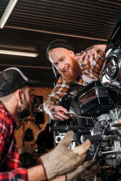 szép mechanika javításkor motorkerékpár együtt garázsban beszél - Fotó, kép