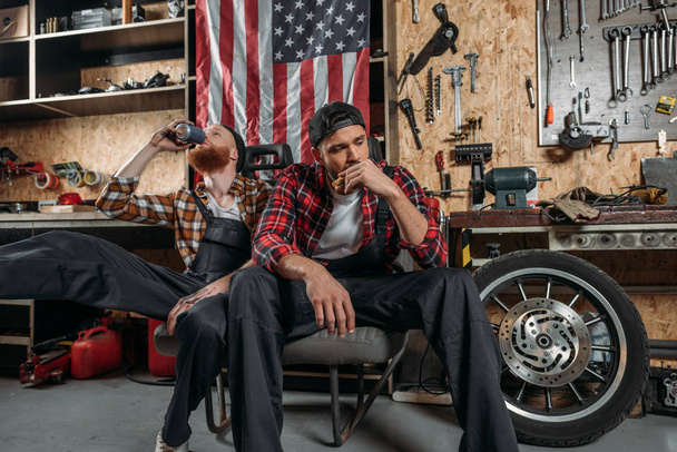 Erschöpfte Mechaniker beim gemeinsamen Mittagessen in der Garage - Foto, Bild