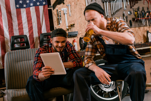 giovani meccanici che bevono birra e usano tablet insieme in garage
 - Foto, immagini