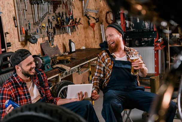 mecánica de la risa con tableta y cerveza en el garaje
 - Foto, Imagen