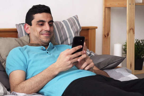 Happy Araba pomocí smartphone, ležící na posteli doma - Fotografie, Obrázek