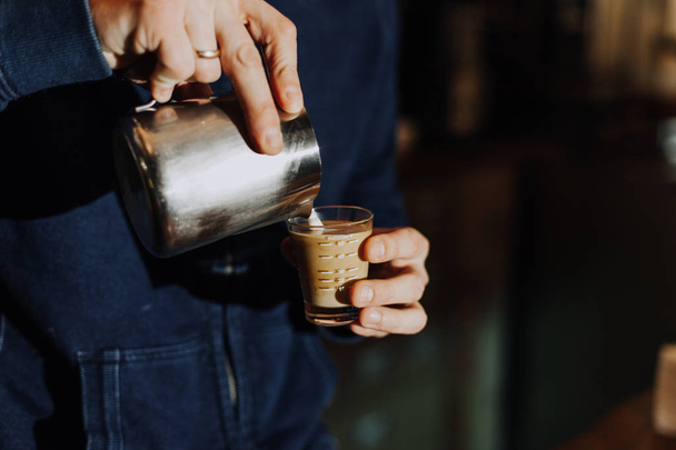 Бариста парит молоко в кувшине с кофеваркой готовится сделать латте искусства в кафе
 - Фото, изображение