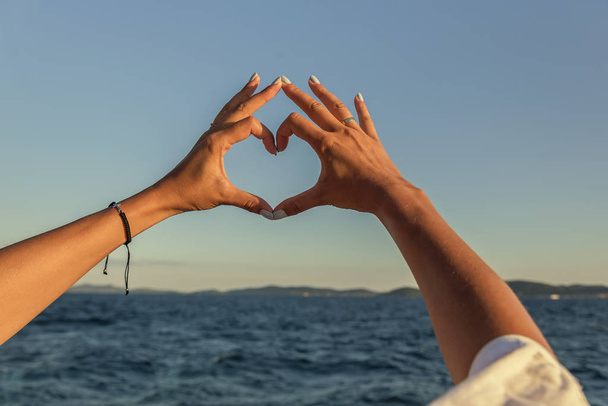 Hands in the shape of heart against the background of the sea. - Fotó, kép