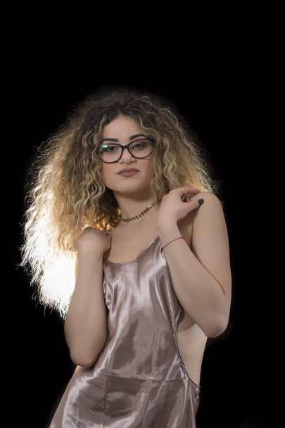 Woman with curly hair and satin lingerie posing on black background - Fotografie, Obrázek