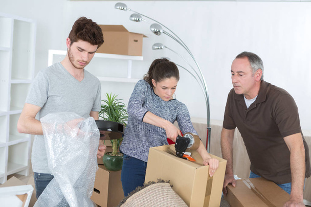 family packing cardboard boxes in living room - Foto, imagen