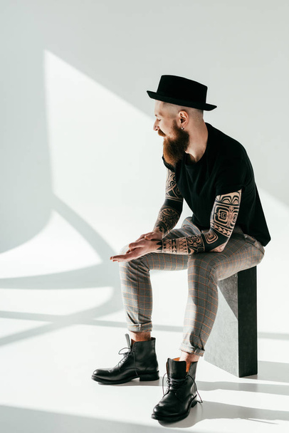 handsome bearded tattooed man sitting on white - Foto, Imagem