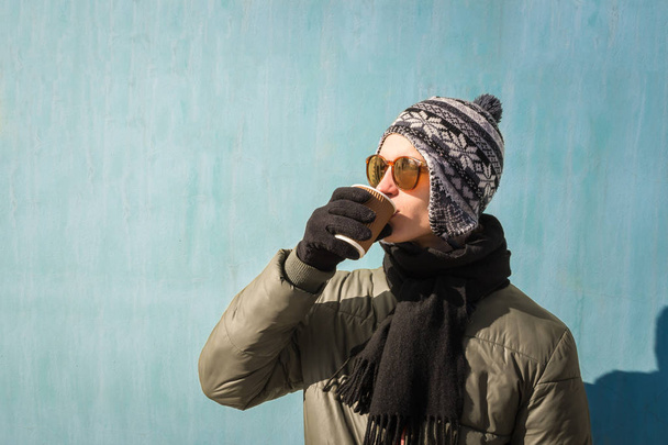 Young man in winter clothes holds cup of coffee - Fotografie, Obrázek