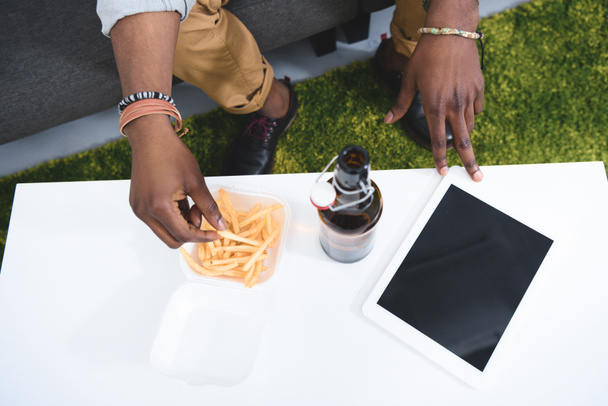 Africam uomo americano mangiare patatine fritte con birra sul tavolo con tablet digitale
 - Foto, immagini