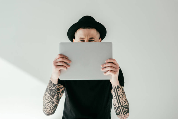 handsome tattooed man looking out from laptop on white - Fotografie, Obrázek