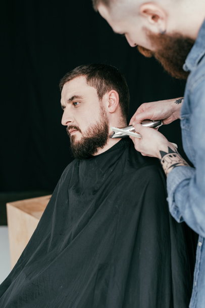 barber trimming customer beard at barbershop - Foto, imagen